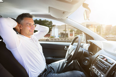 一个轻松成熟的人坐在自主驾驶汽车的侧面视图照片