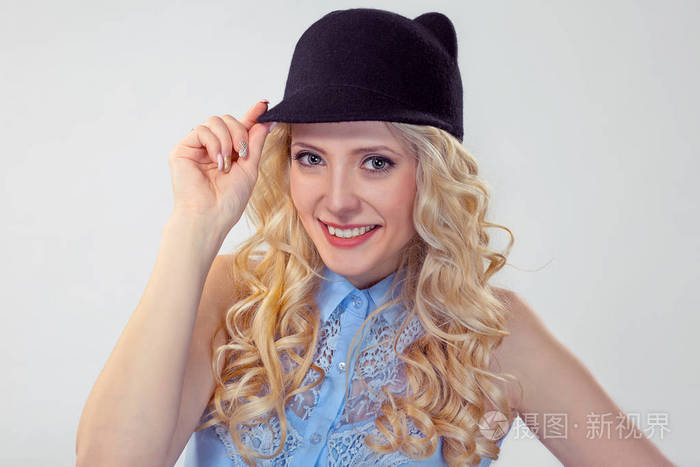 特写肖像年轻美丽的微笑的女人, 握住触摸滑稽的帽子在问候看着你的