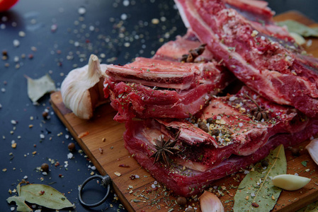 新鲜的原料肉。香料和大蒜。在黑色背景上的切菜板。顶视图，副本空间