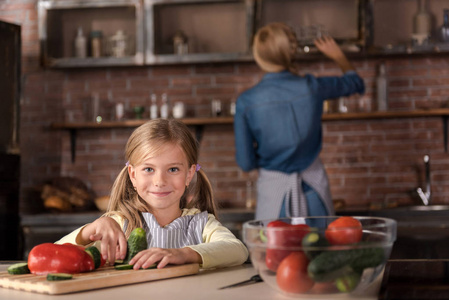 微笑触摸蔬菜在厨房里的小女孩