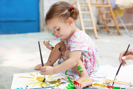 可爱的小高加索女孩喜欢在后院画纸, 水颜色和艺术刷子。选择性聚焦