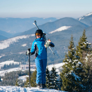 快乐的女子滑雪运动员，站在她肩上，令人惊叹的风景滑雪板的山顶上。山，森林背景 copyspace 冬天雪山自然休闲度假村