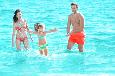 快乐的父母在水中玩耍的小女孩
