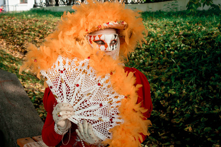 少女在西装 秋天 在狂欢节面具在秋天树的背景
