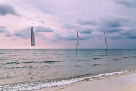 海滩上有白色旗帜的阴沉的热带日落。泰国