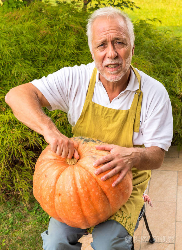 花园里有大橙色南瓜的老人