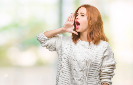 年轻美丽的女人在与世隔绝的背景下穿着冬天的毛衣喊着大声尖叫到一边