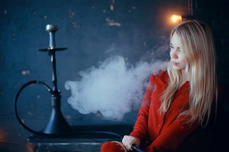 有吸引力的年轻金发女子在红色衣服吸烟水烟照片