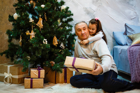 小女孩与祖父坐在圣诞树在家愉快