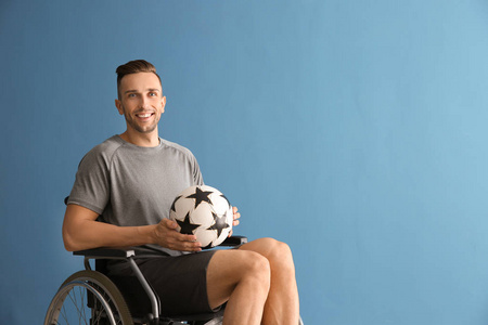 年轻人与球坐在轮椅反对颜色背景