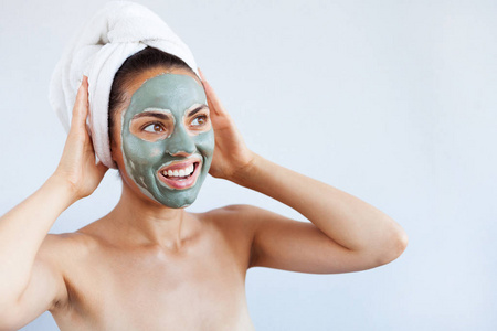 年轻漂亮的女人脸上戴着面膜治疗蓝泥。水疗治疗, 自我护理和健康肌肤。复制空间, 白色背景