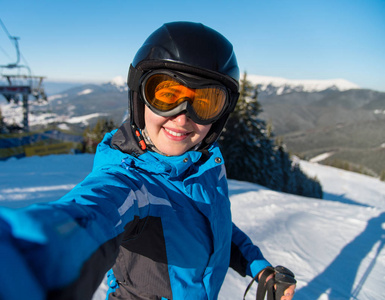 幸福的女人滑雪者笑着，同时拍照后上美丽阳光明媚的冬日 Bukovel，乌克兰喀尔巴阡山区滑雪度假村滑雪斜坡上休息的特写肖像
