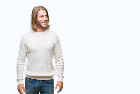 长头发的年轻英俊的人穿着冬天的毛衣在孤立的背景看着一边微笑着脸, 自然的表达。笑的自信