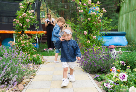 穿着白色运动鞋的小女孩走在村里的花园里。在村里的家庭休息