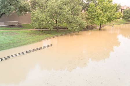 洪水蔓延在达拉斯沃思堡地区, 得克萨斯州, 美国, 淹没路径与金属围栏附近的河畔附近。淹没活橡树