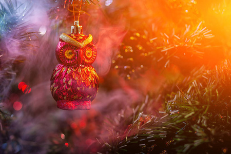 红色闪亮的装饰圣诞球猫头鹰与房子在彩色紫红色烟雾, 在圣诞树背景。现代圣诞贺卡的概念