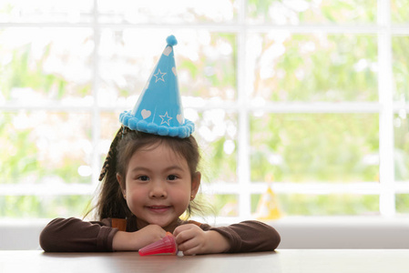 亚洲小孩戴生日帽是微笑。复制空间