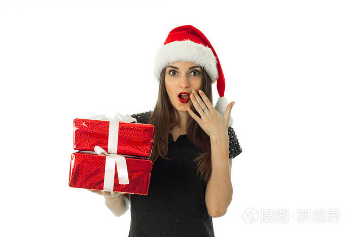 可爱的女孩在圣诞老人的帽子与红色礼品盒