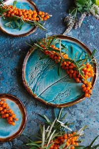 在蓝色混凝土背景上手工陶瓷板上新鲜成熟橙 sandthorn 的顶部视图