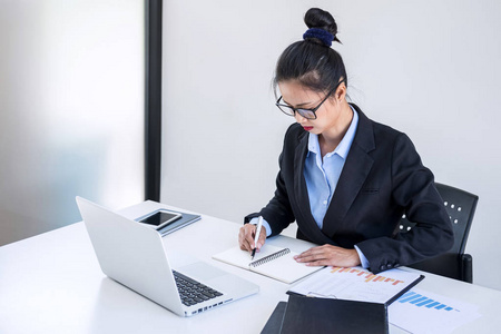 智能女性女实业家在笔记本电脑上工作分析业务战略和销售业绩合同在工作场所