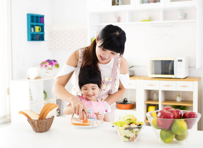 帮助她的妈妈在厨房里做饭的小女孩