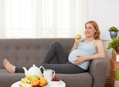 孕妇与盘水果和茶