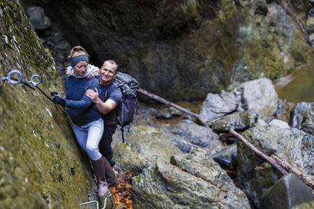 夫妇的徒步旅行者爬上安全电缆在峡谷上面