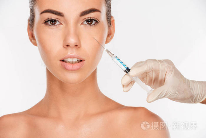 美丽的女人获取美容注射在眼睛区域与注射器