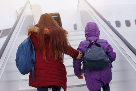 快乐的游客两个背包的女孩登上阶梯飞机