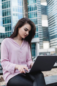 年轻的企业妇女使用膝上型电脑工作, 而坐在外面, 美丽的忙碌的女人打字便携式计算机为远程工作, 黑发女商人远程工作在 pc 上的