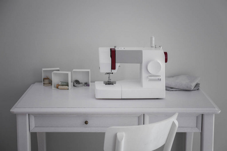 现代缝纫机与裁缝的供应在桌附近轻的墙壁