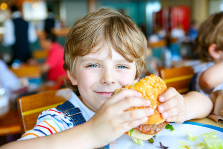 可爱健康学龄前孩子吃汉堡包坐在咖啡馆户外