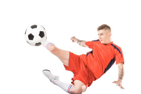 年轻的足球运动员踢球在跳跃隔绝白色