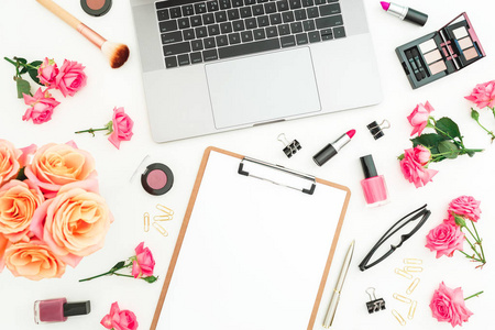 笔记本电脑, 剪贴板, 玫瑰花, 化妆品和配件的白色背景。平躺。顶部视图。女性自由职业者办公室概念