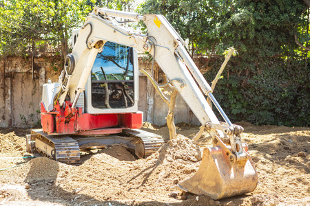 挖掘区域挖掘机, 反铲工作在土壤上清除树木旁边的区域为新的公园大厦