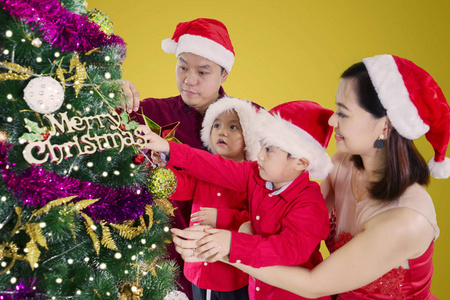 亚洲家庭一起装饰圣诞树同时戴着圣诞帽