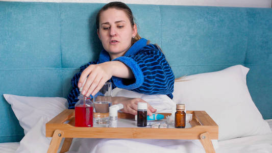 年轻女子的画像躺在床上, 从托盘服药