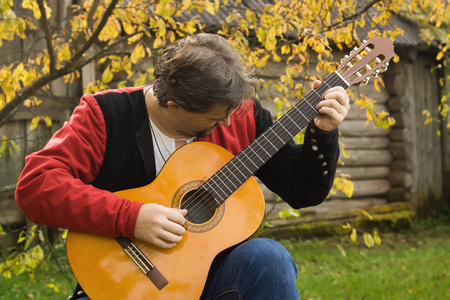 秋天的花园里的吉他的男人