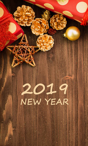 圣诞节和元旦节日装饰, 金球, 木制的星星与礼物包裹在红色的纸与金色的圆圈在棕色木头背景与文本2019新年。平躺着。从上面看