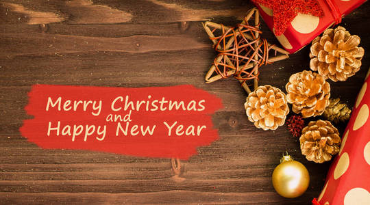 圣诞节和元旦节日的装饰, 金球, 金色的冷杉锥和木星与两个礼物包裹在红色的纸与金色圆圈在棕色木头背景。平躺着。从上面看文字圣诞快