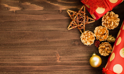 圣诞节和元旦节日的装饰, 金球, 金色的冷杉锥和木星与两个礼物包裹在红色的纸与金色圆圈在棕色木头背景。平躺着。从上面看。复制文本