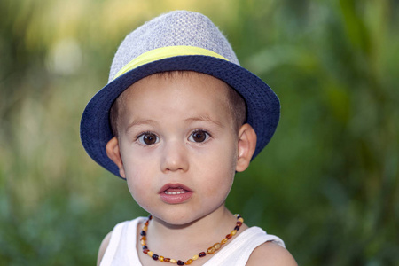 一个可爱的小男孩的肖像, 戴帽子, 而站在外面一个美丽的阳光明媚的夏日。他出去玩了, 看着镜头。复制空间