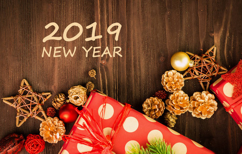 圣诞节和元旦节日节日装饰, 红色和金色的球, 冷杉锥和木星与礼物包裹在红色纸与金色圆圈在棕色木头背景与文本2019新年。平躺着。