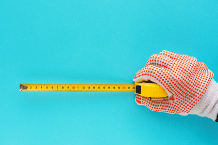 用带米的杂工测量尺寸, 手与在蓝色背景下被隔绝的工具照片