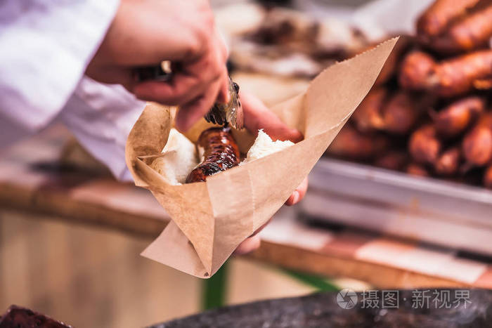 合手手持自制香肠烤在纸袋包装的烤架上, 有选择性的焦点和小深度的景深