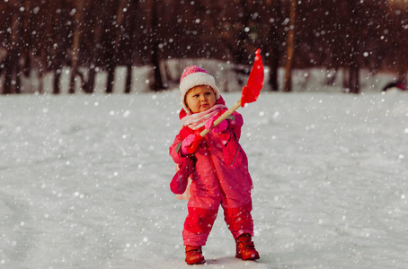 可爱的小姑娘蹒跚学步挖冬天的雪