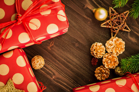 圣诞节和元旦节日节日装饰, 红色和金色的球, 五颜六色的冷杉锥和树枝, 明星与三个礼物包裹在红色的纸与金色的圆圈在棕色木头背景。