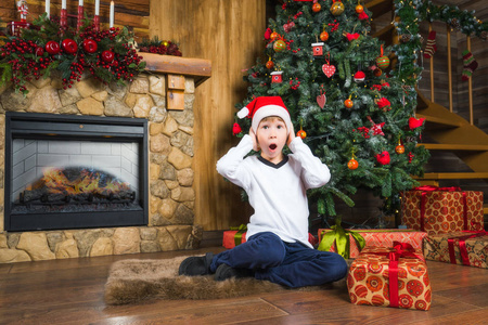 小男孩穿着与礼物的圣诞帽子失望