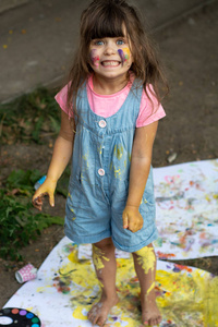 惊讶或震惊的孩子的肖像有乐趣与手油漆。有趣的小女孩与彩色的脸使用水彩画