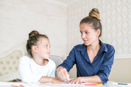 母女俩一起画画.成年妇女帮助儿童女孩照片